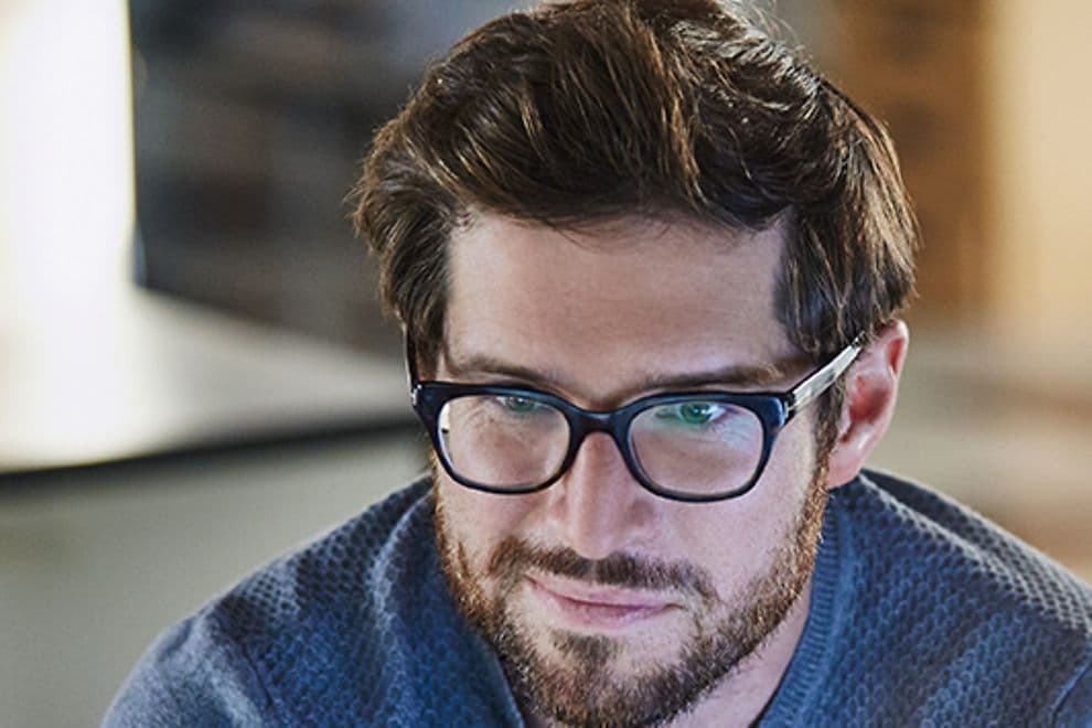 man in glasses looking at laptop