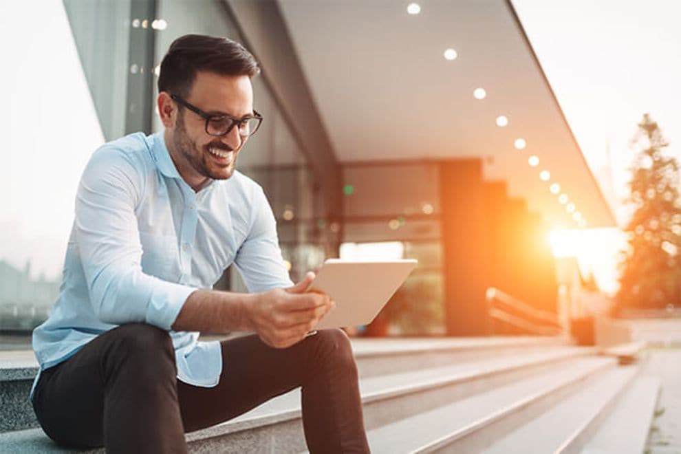 Man using a tablet, sitting on stairs